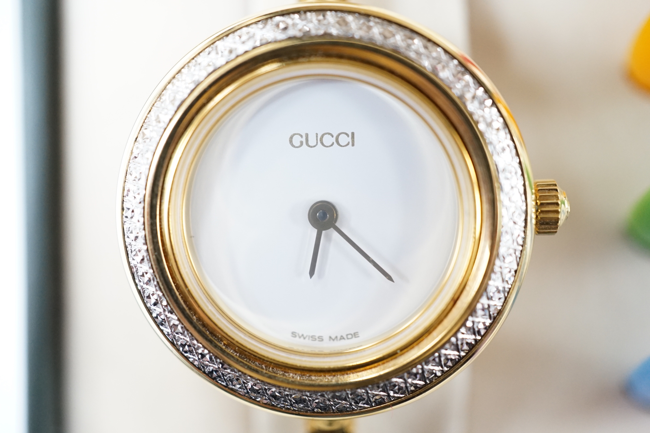A lady's modern gilt Gucci quartz bangle wrist watch, with twelve interchangeable bezels, in original Gucci box.